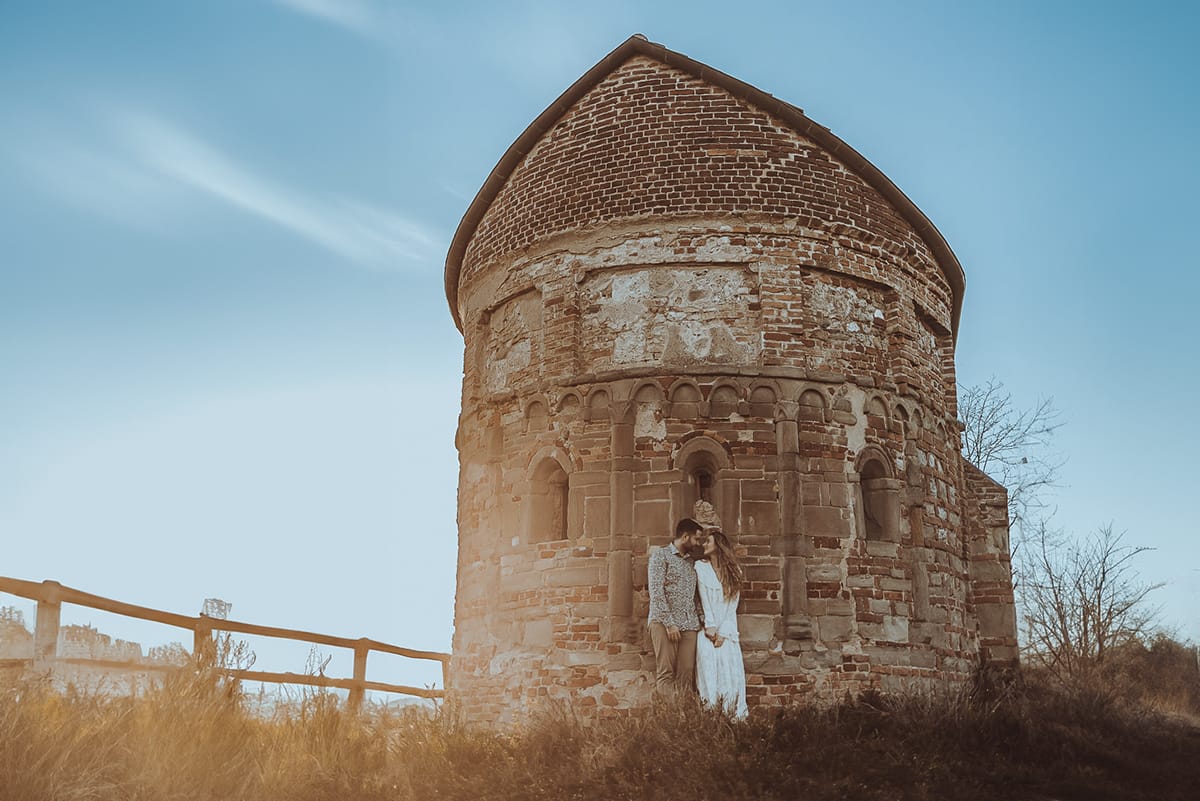 Un ritratto romantico di Anita e Davide, futuri sposi, in una soleggiata giornata primaverile. La coppia si trova di fronte a una chiesetta romanica a Mombello di Torino, nel cuore del Monferrato