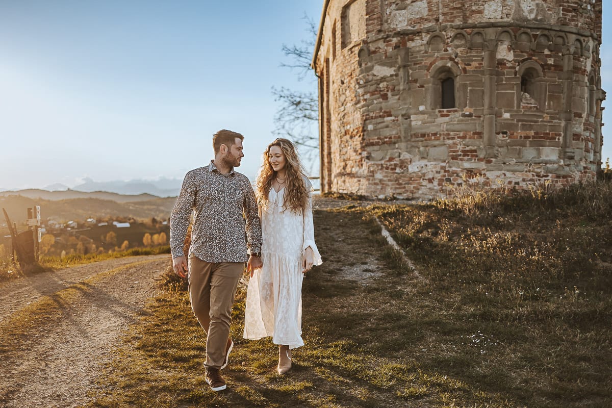 Un ritratto romantico di Anita e Davide, futuri sposi, in una soleggiata giornata primaverile. La coppia si trova di fronte a una chiesetta romanica a Mombello di Torino, nel cuore del Monferrato