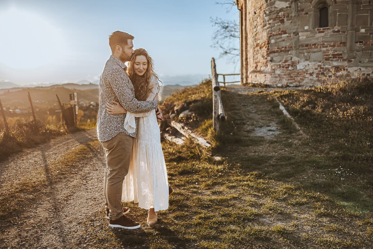 Un ritratto romantico di Anita e Davide, futuri sposi, in una soleggiata giornata primaverile. La coppia si trova di fronte a una chiesetta romanica a Mombello di Torino, nel cuore del Monferrato