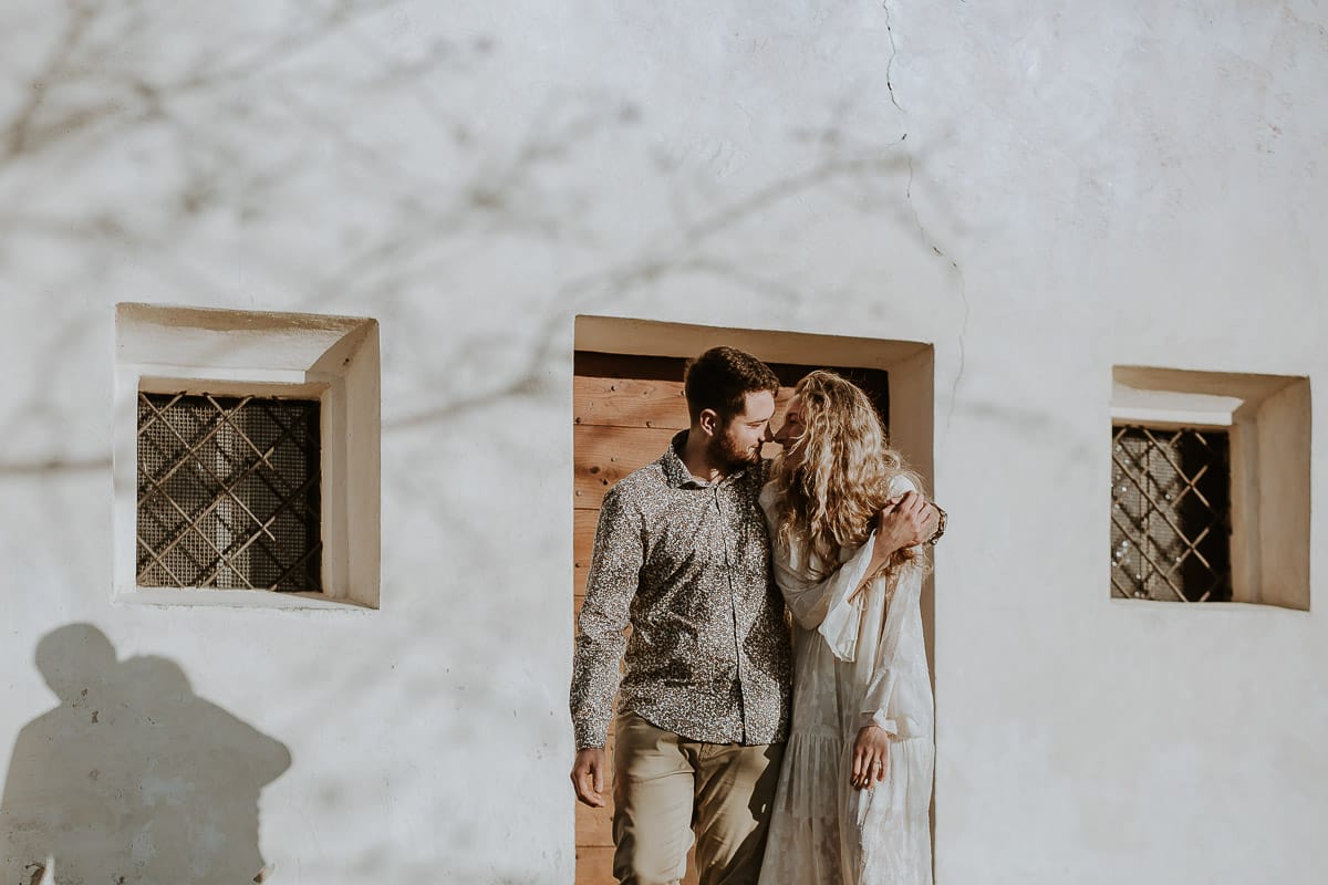 Mombello di Torino, Monferrato: Anita e Davide, raggianti di felicità, si scambiano un bacio davanti a una chiesetta romanica in un pittoresco pomeriggio primaverile. La foto cattura l'amore e l'emozione che precedono il loro matrimonio.