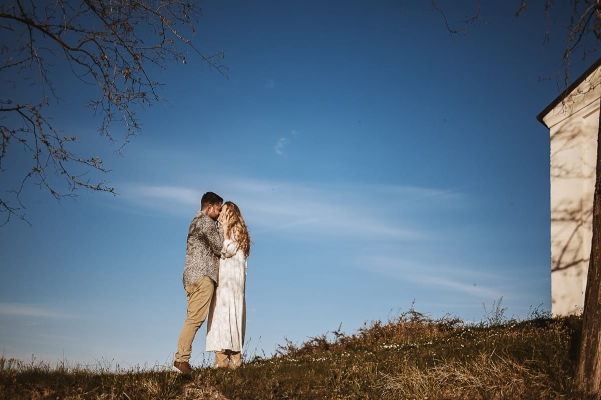 Mombello di Torino, Monferrato: Anita e Davide, raggianti di felicità, si scambiano un bacio davanti a una chiesetta romanica in un pittoresco pomeriggio primaverile. La foto cattura l'amore e l'emozione che precedono il loro matrimonio