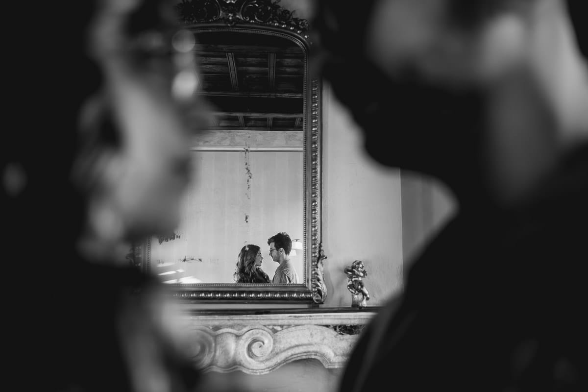 Fotografo matrimonio Rivalba. Villa Ala. Prewedding di Giorgia e Marco. Coppia in una sala della villa . riflessi nella specchiera sul camino