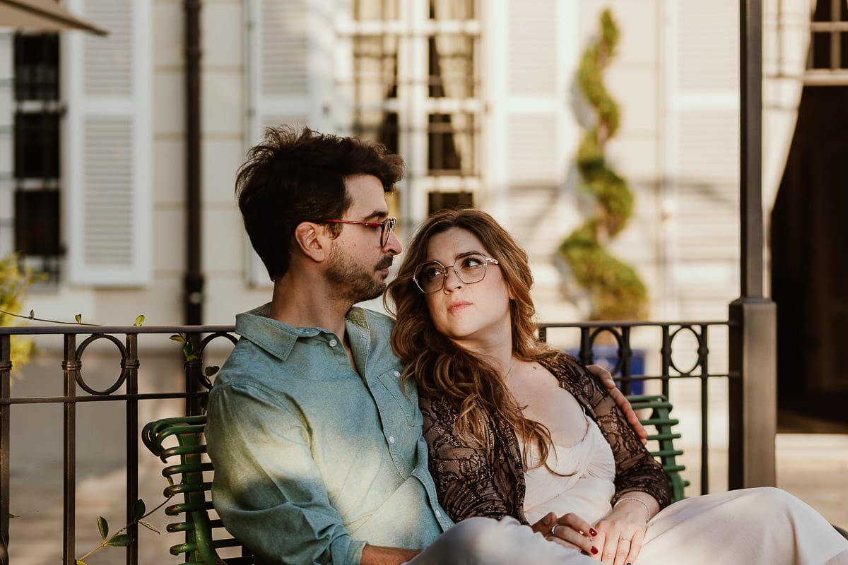 Fotografo matrimonio Rivalba. Villa Ala. Prewedding di Giorgia e Marco. Golden Hour. La coppia è seduti su di una panchina di ferro battuto, davanti alla villa sotto un gazebo in ferro battuto. la coppia su guarda
