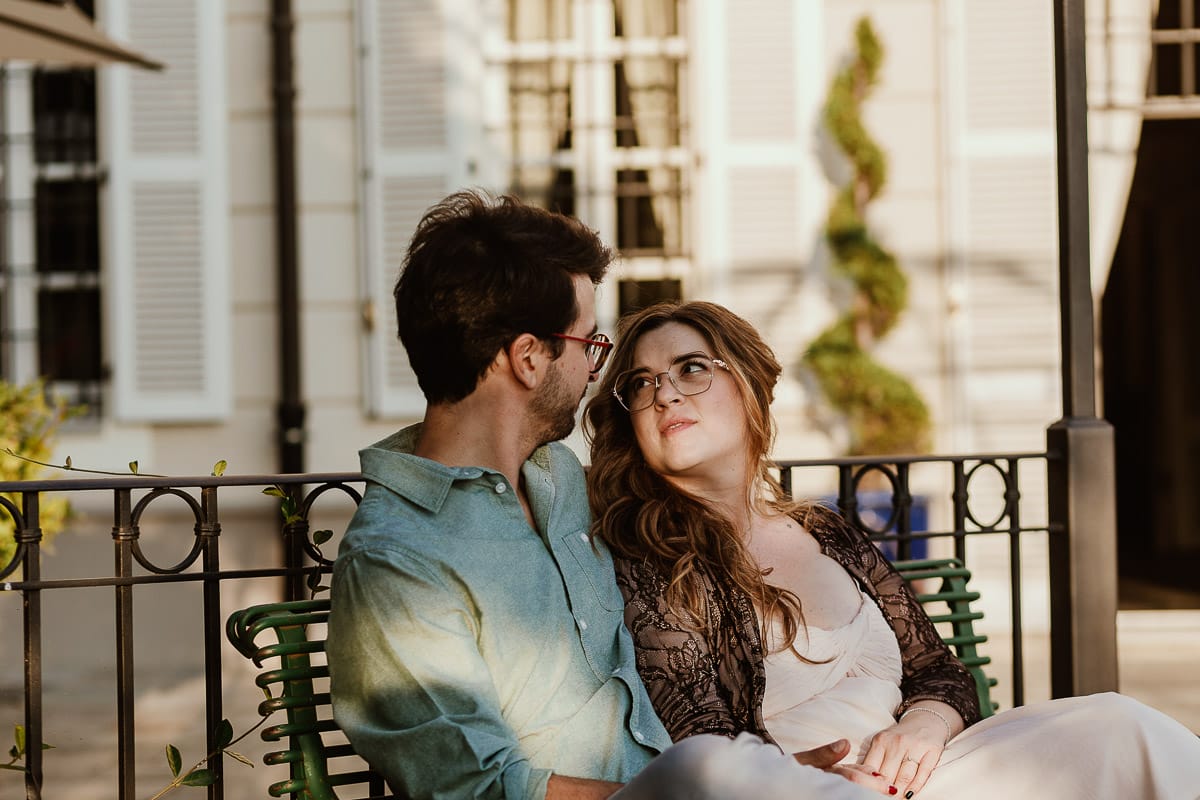 Fotografo matrimonio Rivalba. Villa Ala. Prewedding di Giorgia e Marco. Golden Hour. La coppia è seduti su di una panchina di ferro battuto, davanti alla villa sotto un gazebo in ferro battuto.