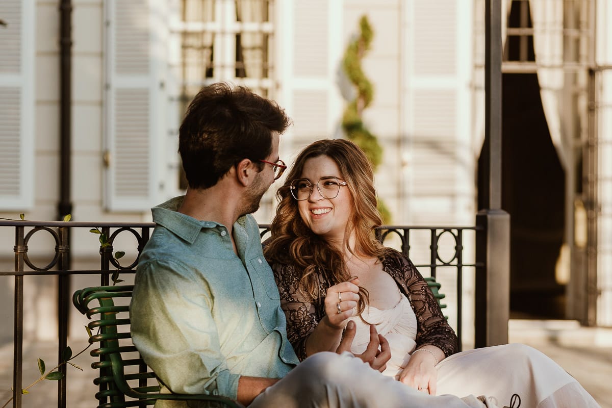 Fotografo matrimonio Rivalba. Villa Ala. Prewedding di Giorgia e Marco. Golden Hour. La coppia è seduti su di una panchina di ferro battuto, davanti alla villa sotto un gazebo in ferro battuto.