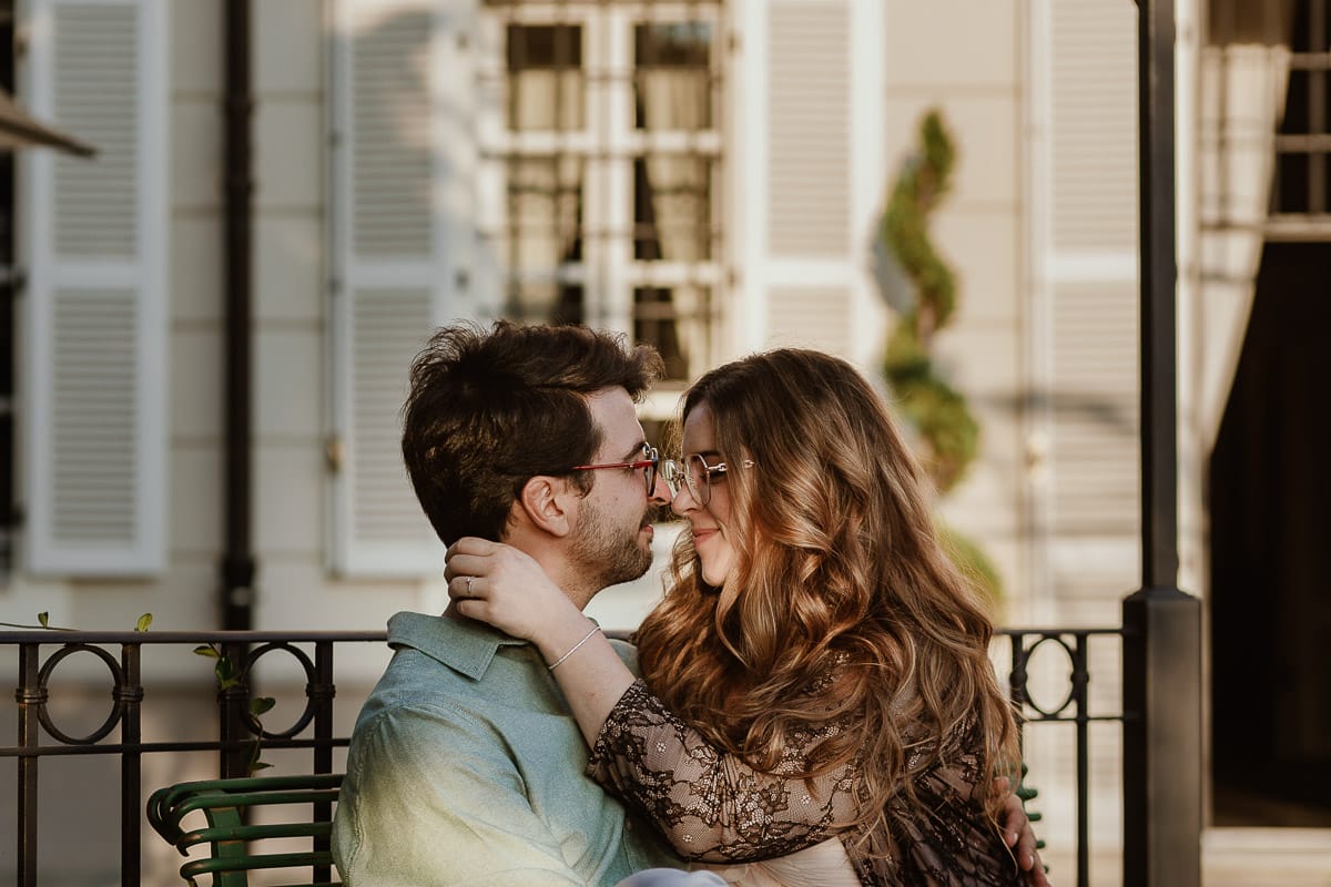 Fotografo matrimonio Rivalba. Villa Ala. Prewedding di Giorgia e Marco. Golden Hour. La coppia è seduti su di una panchina di ferro battuto, davanti alla villa sotto un gazebo in ferro battuto. La coppia è fronte fronte