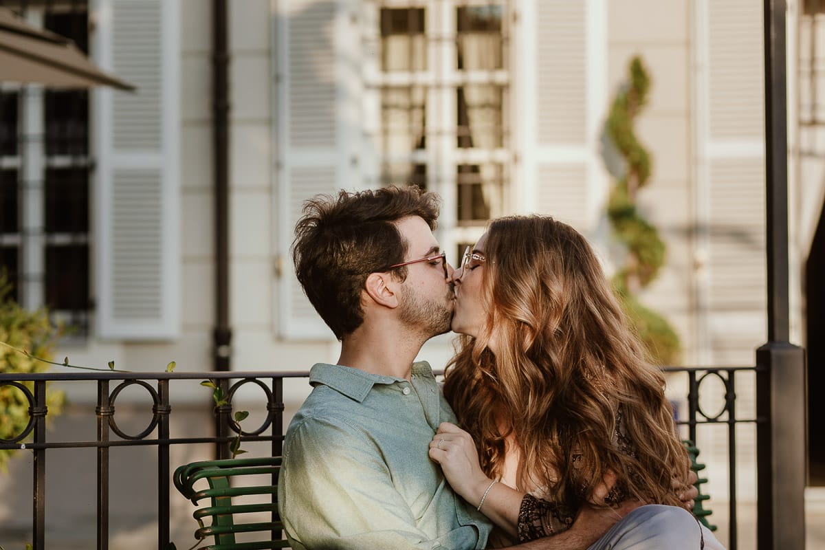 Fotografo matrimonio Rivalba. Villa Ala. Prewedding di Giorgia e Marco. Golden Hour. La coppia è seduti su di una panchina di ferro battuto, davanti alla villa sotto un gazebo in ferro battuto. Bacio