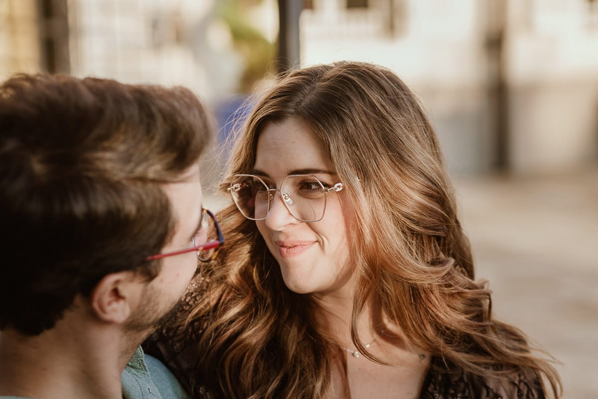 Fotografo matrimonio Rivalba. Villa Ala. Prewedding di Giorgia e Marco. Golden Hour. La coppia è seduti su di una panchina di ferro battuto, davanti alla villa sotto un gazebo in ferro battuto. Ritratto ravvicinato. Giorgia guarda Marco teneramente e sorride