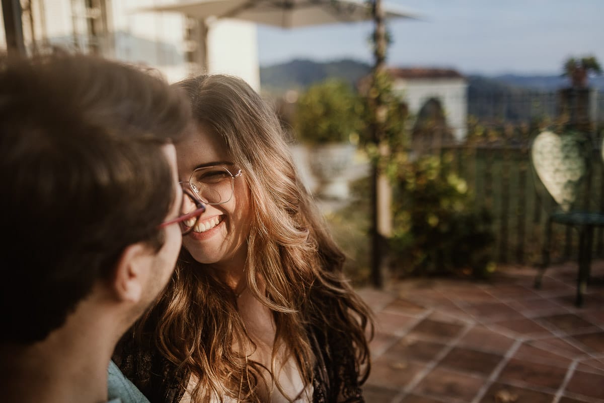 Fotografo matrimonio Rivalba. Villa Ala. Prewedding di Giorgia e Marco. Golden Hour. La coppia è seduti su di una panchina di ferro battuto, davanti alla villa sotto un gazebo in ferro battuto. Ritratto ravvicinato. Giorgia guarda Marco teneramente