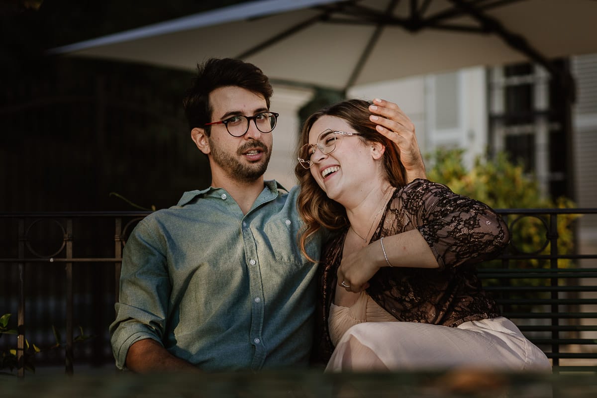 Fotografo matrimonio Rivalba. Villa Ala. Prewedding di Giorgia e Marco. Golden Hour. La coppia è seduti su di una panchina di ferro battuto, davanti alla villa sotto un gazebo in ferro battuto. Ritratto