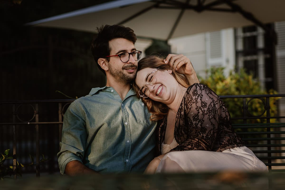 Fotografo matrimonio Rivalba. Villa Ala. Prewedding di Giorgia e Marco. Golden Hour. La coppia è seduti su di una panchina di ferro battuto, davanti alla villa sotto un gazebo in ferro battuto. Ritratto . Giorgia appoggia la testa sulla spalla di Marco.