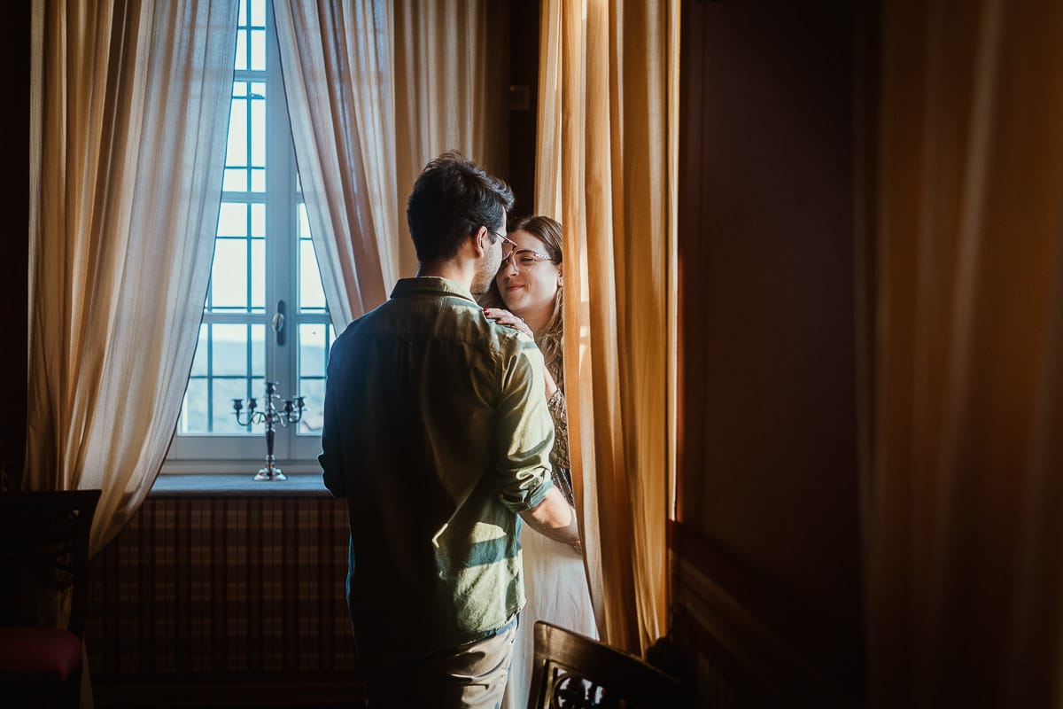 Fotografo matrimonio Rivalba. Villa Ala. Prewedding di Giorgia e Marco. Golden Hour. Ritratto vicino ad una finestra tra i tendaggi gialli.