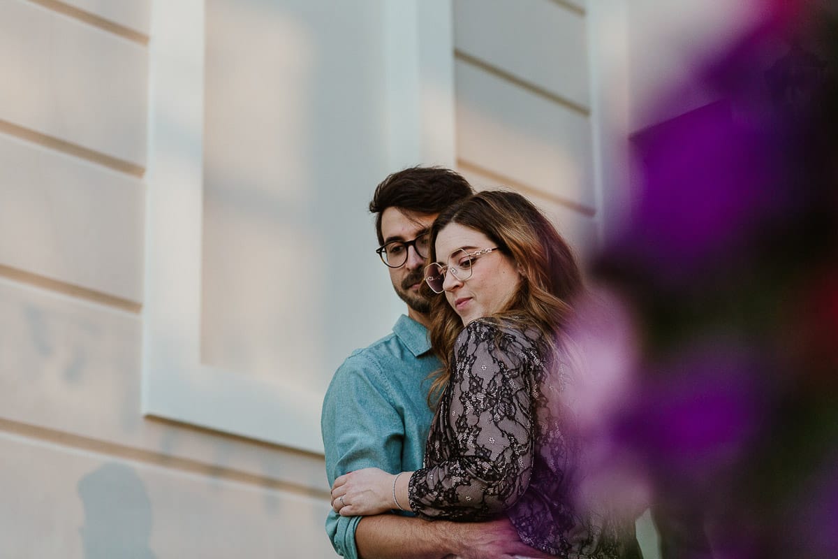 Fotografo matrimonio Rivalba. Villa Ala. Prewedding di Giorgia e Marco. Golden Hour. La coppia esce dalla villa. Ritratto ripreso attraverso un vaso di fiori.
