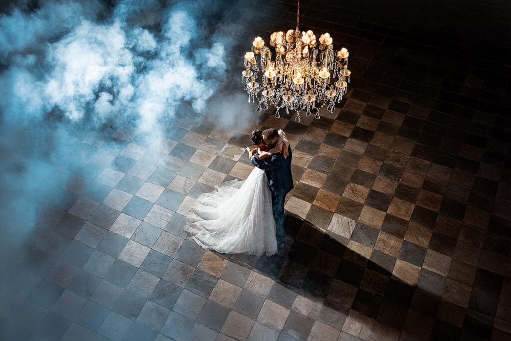 Tendenzem matrimoni 2025/26 Fotografo matrimonio  Torino Fotografia emozionante del ballo degli sposi al Castello Canalis nel salone delle feste con il grande lampadario a gocce e il fumo.