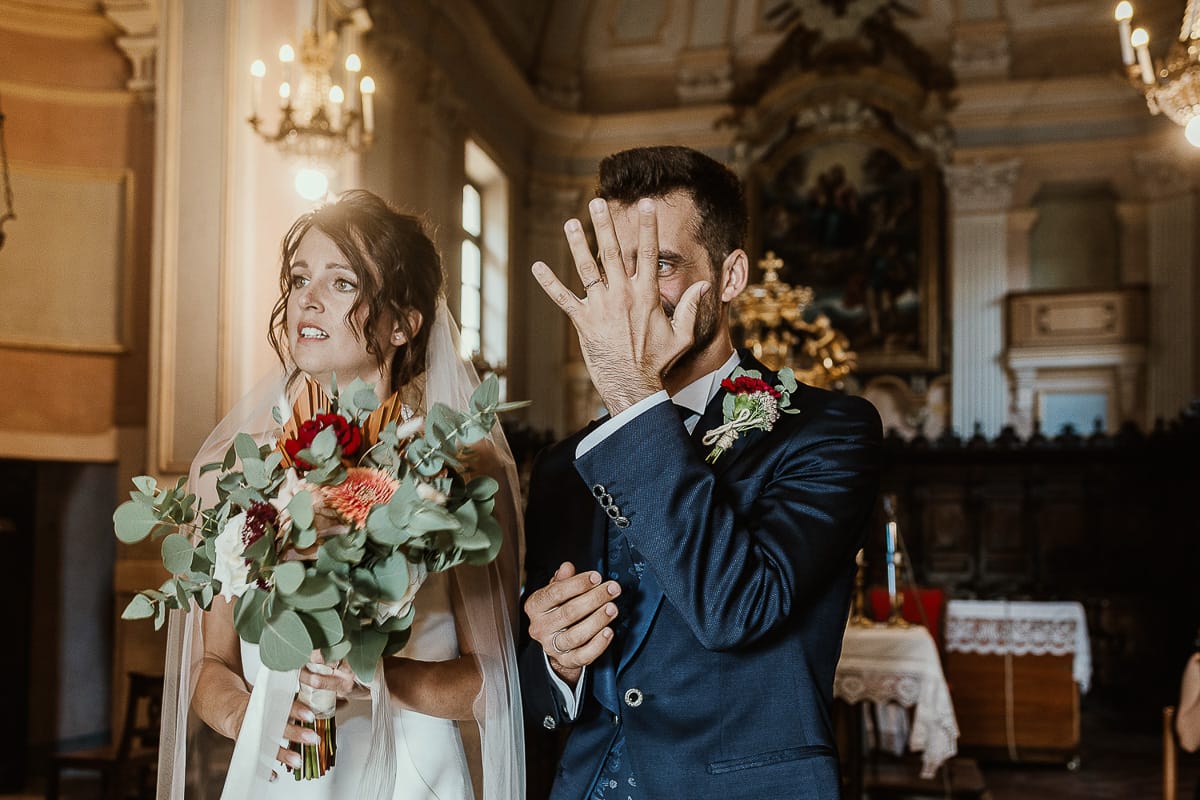 Fotografo matrimonio Torino. Matrimonio eco-consapevole a Cascina Ranverso. Cerimonia a Chieri nella chiesa dei Santi Bernardino e Rocco. Messa. Uscita degli sposi. lo sposo mostra l'anello