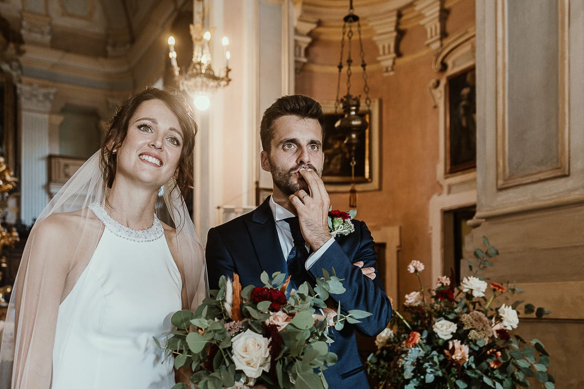 Fotografo matrimonio Torino. Matrimonio eco-consapevole a Cascina Ranverso. Cerimonia a Chieri nella chiesa dei Santi Bernardino e Rocco. Messa. Uscita degli sposi. Lo sposo ha una buffa espressione