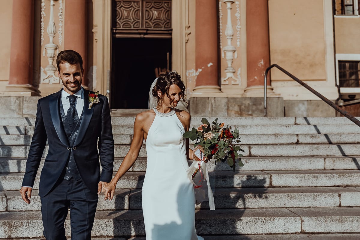 Fotografo matrimonio Torino. Matrimonio eco-consapevole a Cascina Ranverso. Cerimonia a Chieri nella chiesa dei Santi Bernardino e Rocco. Gli sposi scendono le scale della chiesa.