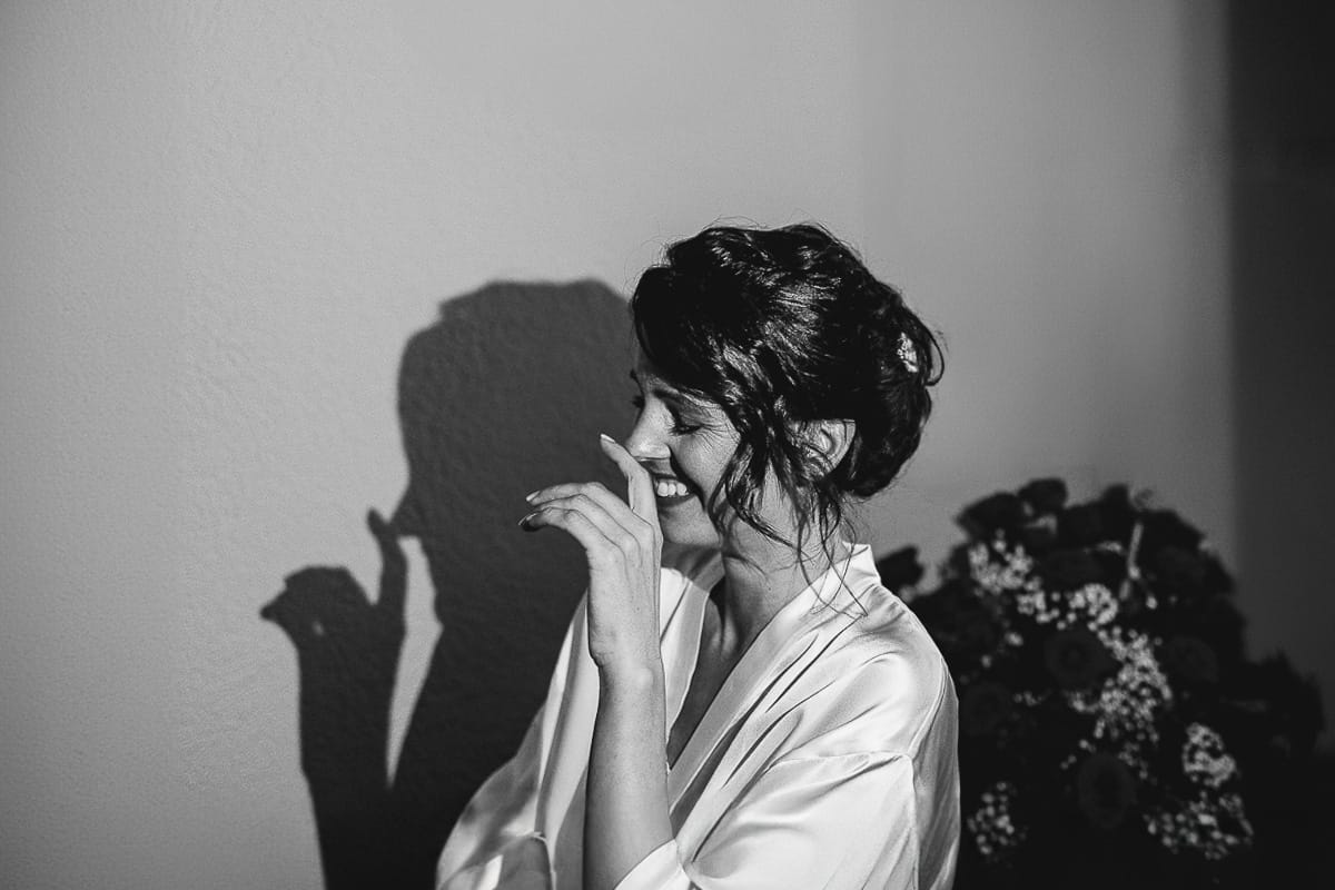 Fotografo matrimonio Torino. Matrimonio eco-consapevole a Cascina Ranverso. Preparazione della sposa a Chieri. Sposa che ride. Bianco e nero.
