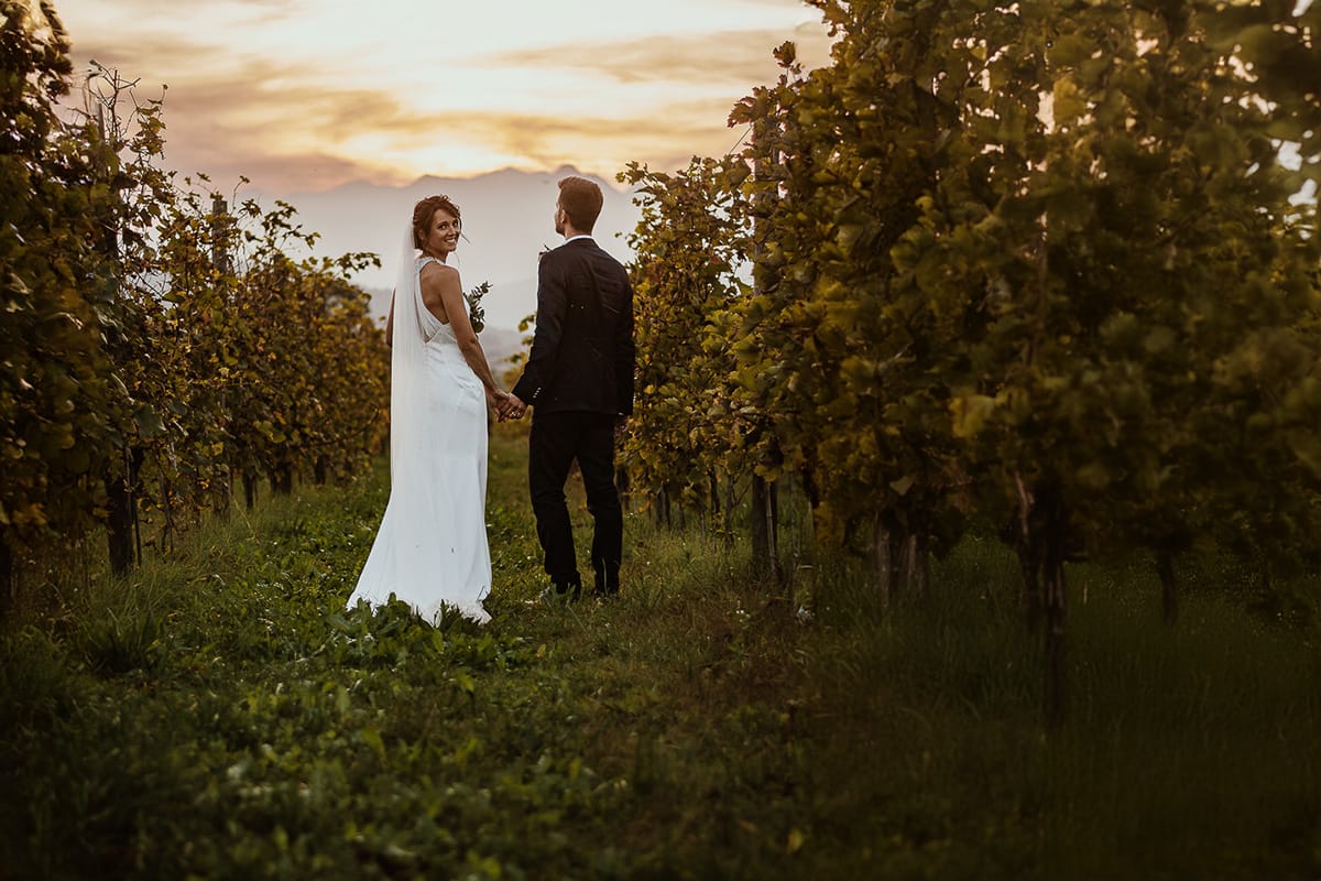 Fotografo matrimonio Torino. Matrimonio eco-consapevole a Cascina Ranverso. Ritratto degli sposi al tramonto. Sposi passeggiano nel vigneto.