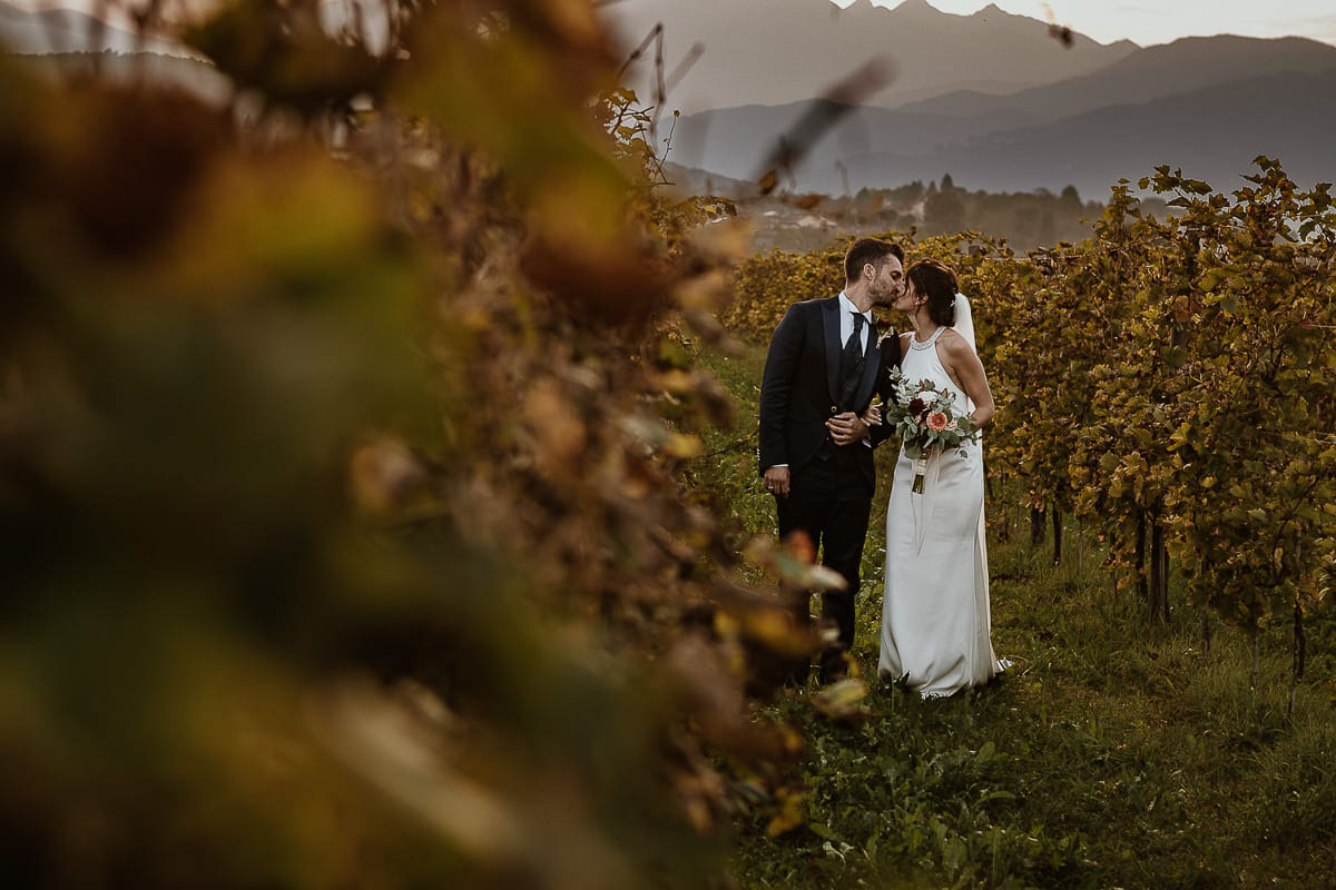Fotografo matrimonio Torino. Matrimonio eco-consapevole a Cascina Ranverso. Ritratto degli sposi al tramonto. Sposi nel vigneto si baciano