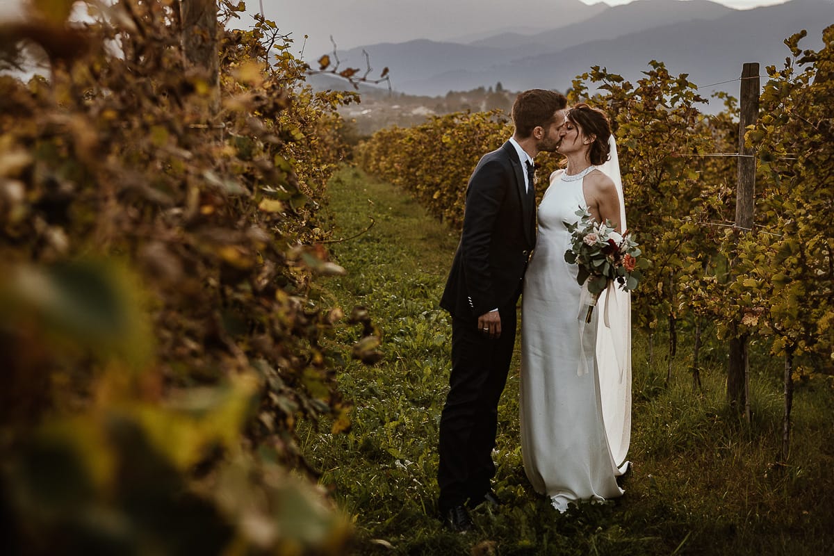 Fotografo matrimonio Torino. Matrimonio eco-consapevole a Cascina Ranverso. Ritratto degli sposi al tramonto. Sposi nel vigneto si baciano