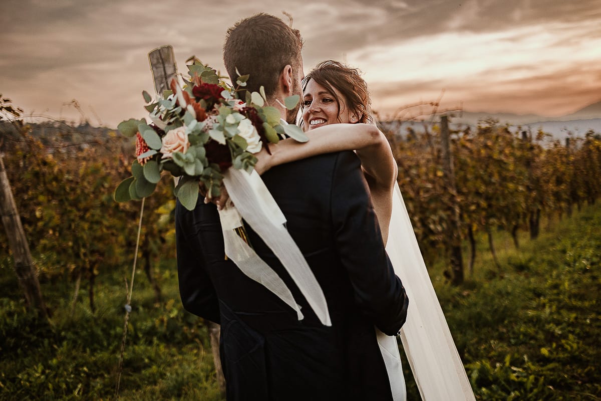 Fotografo matrimonio Torino. Matrimonio eco-consapevole a Cascina Ranverso. Ritratto degli sposi al tramonto. Sposi nel vigneto si abbracciano