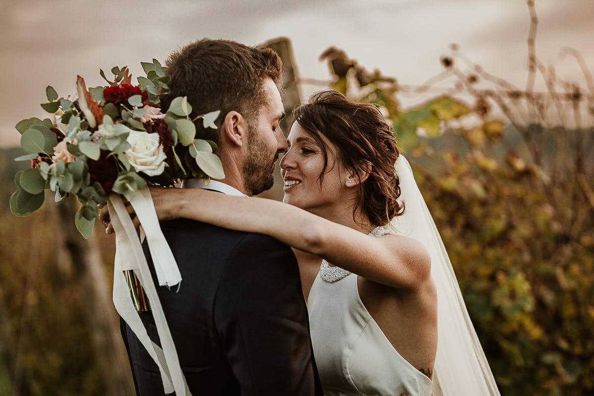 Fotografo matrimonio Torino. Matrimonio eco-consapevole a Cascina Ranverso. Ritratto degli sposi al tramonto. Sposi nel vigneto si abbracciano