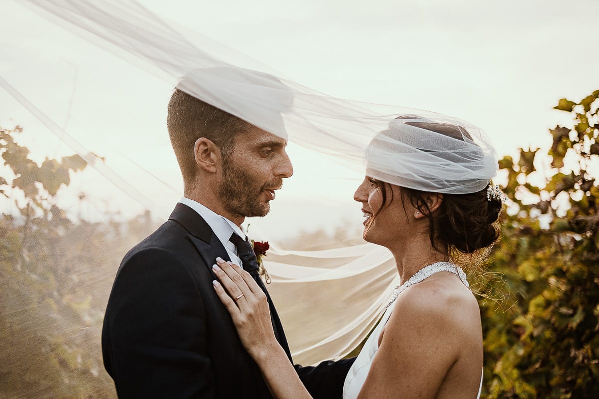 Fotografo matrimonio Torino. Matrimonio eco-consapevole a Cascina Ranverso. Ritratto degli sposi al tramonto. Sposi nel vigneto sotto il velo