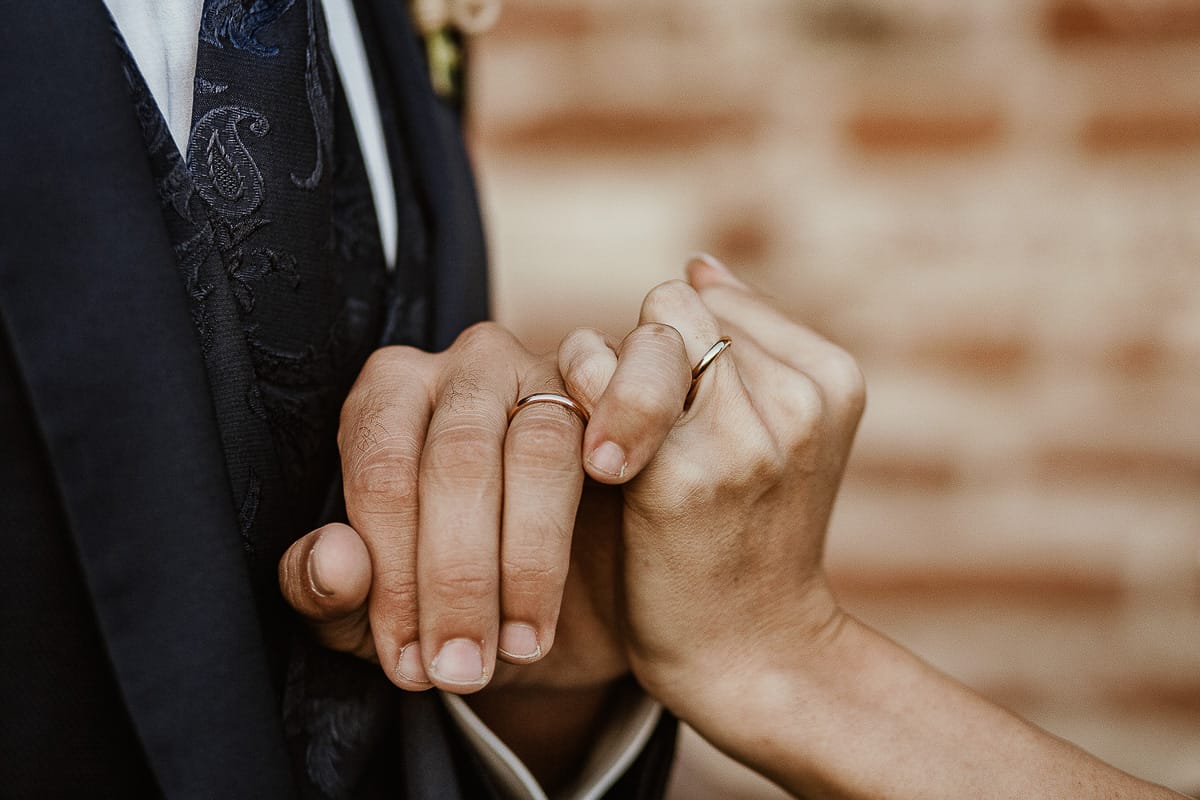 Fotografo matrimonio Torino. Matrimonio eco-consapevole a Cascina Ranverso. Ritratto degli sposi al tramonto. Particolare delle mani
