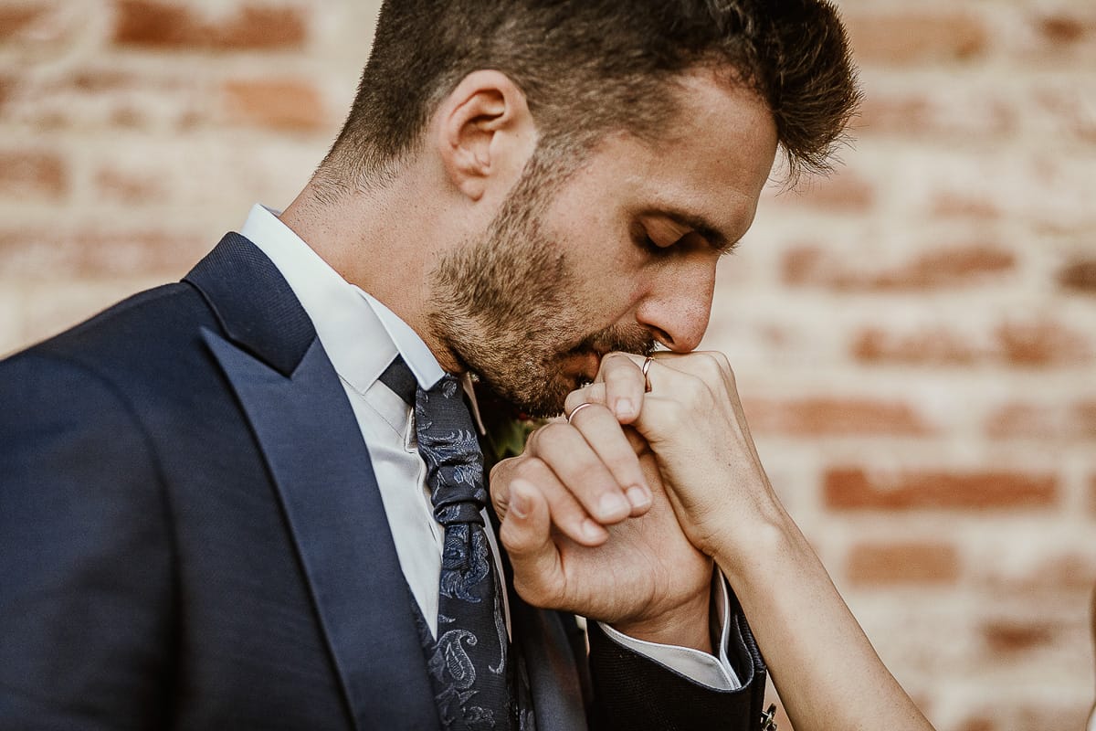 Fotografo matrimonio Torino. Matrimonio eco-consapevole a Cascina Ranverso. Ritratto degli sposi al tramonto. Lo sposo bacia la mano della sposa.