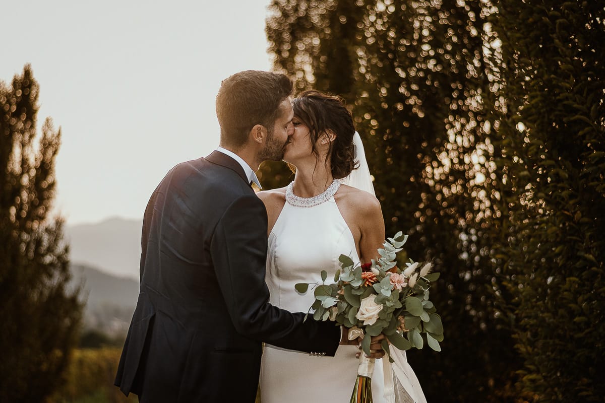 Fotografo matrimonio Torino. Matrimonio eco-consapevole a Cascina Ranverso. Ritratto degli sposi al tramonto. Gli sposi si baciano sul viale che porta nella location