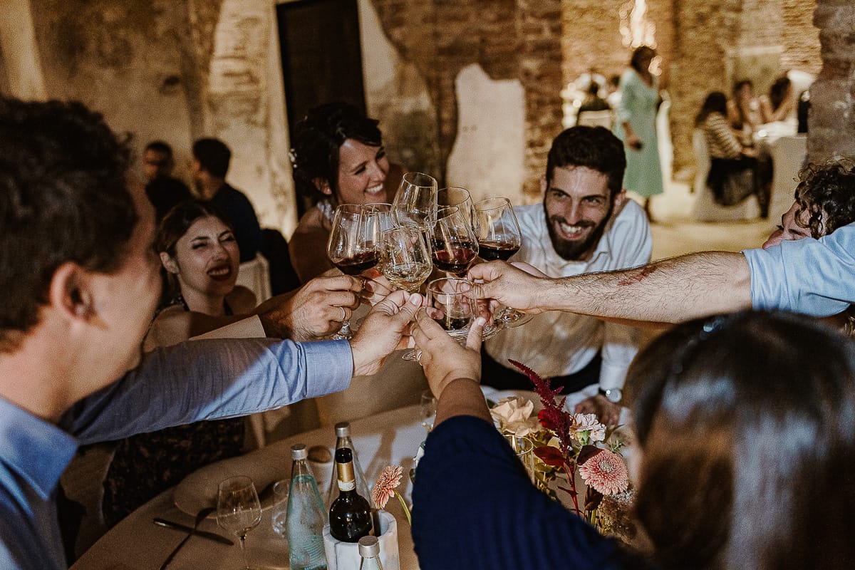 Fotografo matrimonio Torino. Matrimonio eco-consapevole a Cascina Ranverso. Cena. Sposa brinda con gli amici.