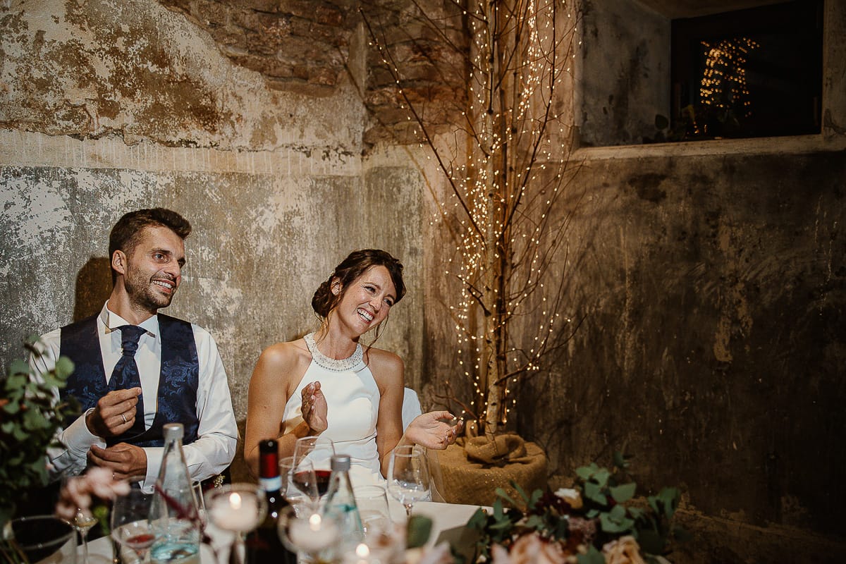 Fotografo matrimonio Torino. Matrimonio eco-consapevole a Cascina Ranverso. Cena. Sposi al tavolo ascoltano i discorsi