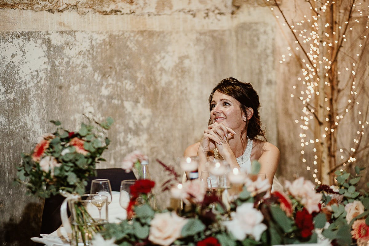 Fotografo matrimonio Torino. Matrimonio eco-consapevole a Cascina Ranverso. Cena. Discorso dello sposo, sposa ascolta guardandolo con amore.