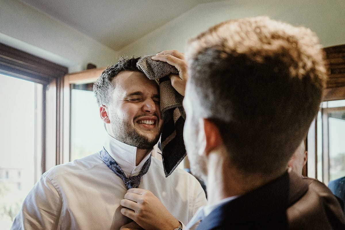 Fotografo matrimonio Torino. Matrimonio eco-consapevole a Cascina Ranverso. Preparazione dello sposo a Chieri. Vestizione dello sposo. Sposo asciuga il fratello.