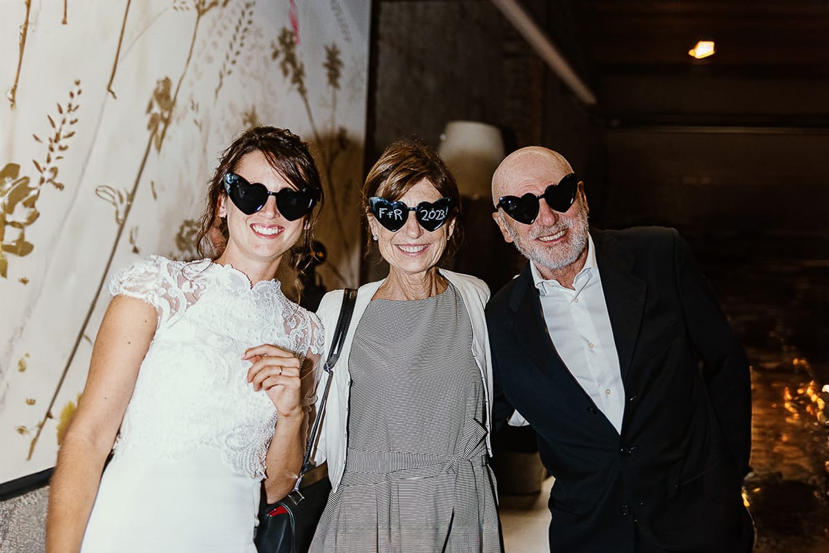 Fotografo matrimonio Torino.eco-consapevole a Cascina Ranverso. Festa. Sposa e Invitati con occhiali a cuore con le iniziali degli sposi