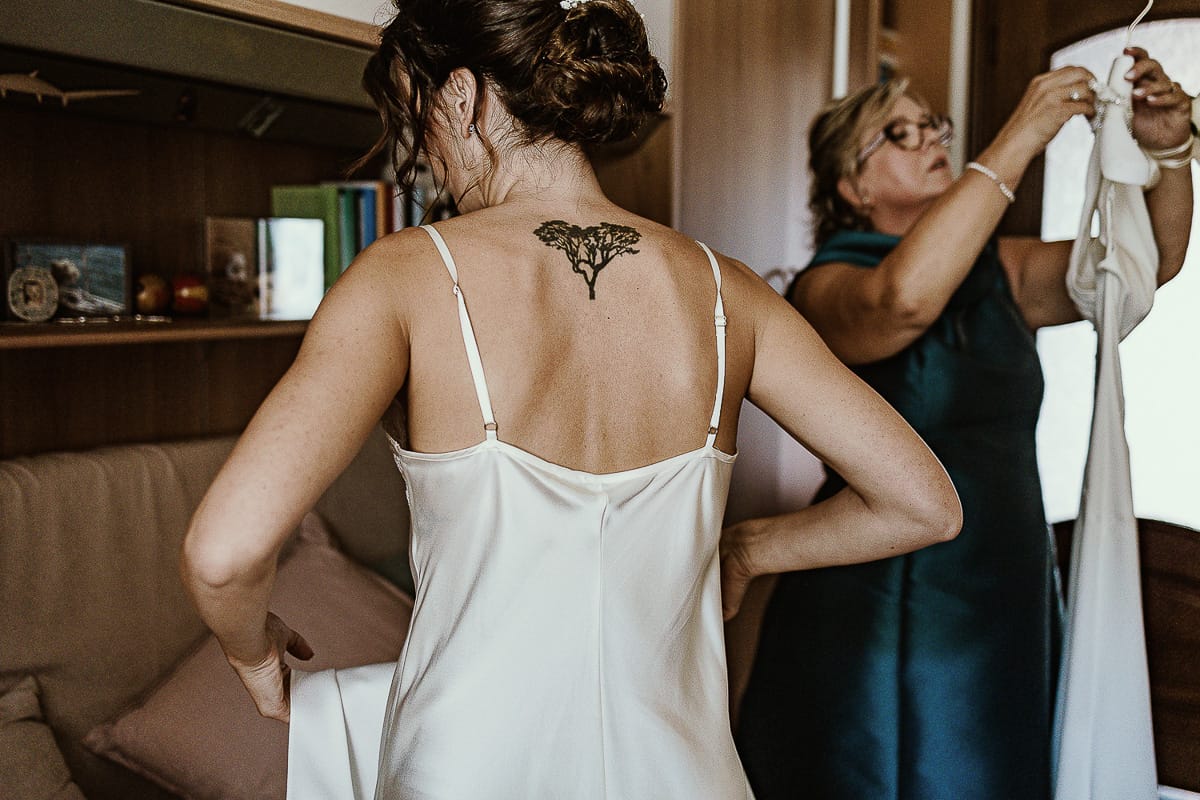 Fotografo matrimonio Torino. Matrimonio eco-consapevole a Cascina Ranverso. Preparazione della sposa a Chieri. Vestizione della sposa. dettaglio sul tatuaggio sulla schiena