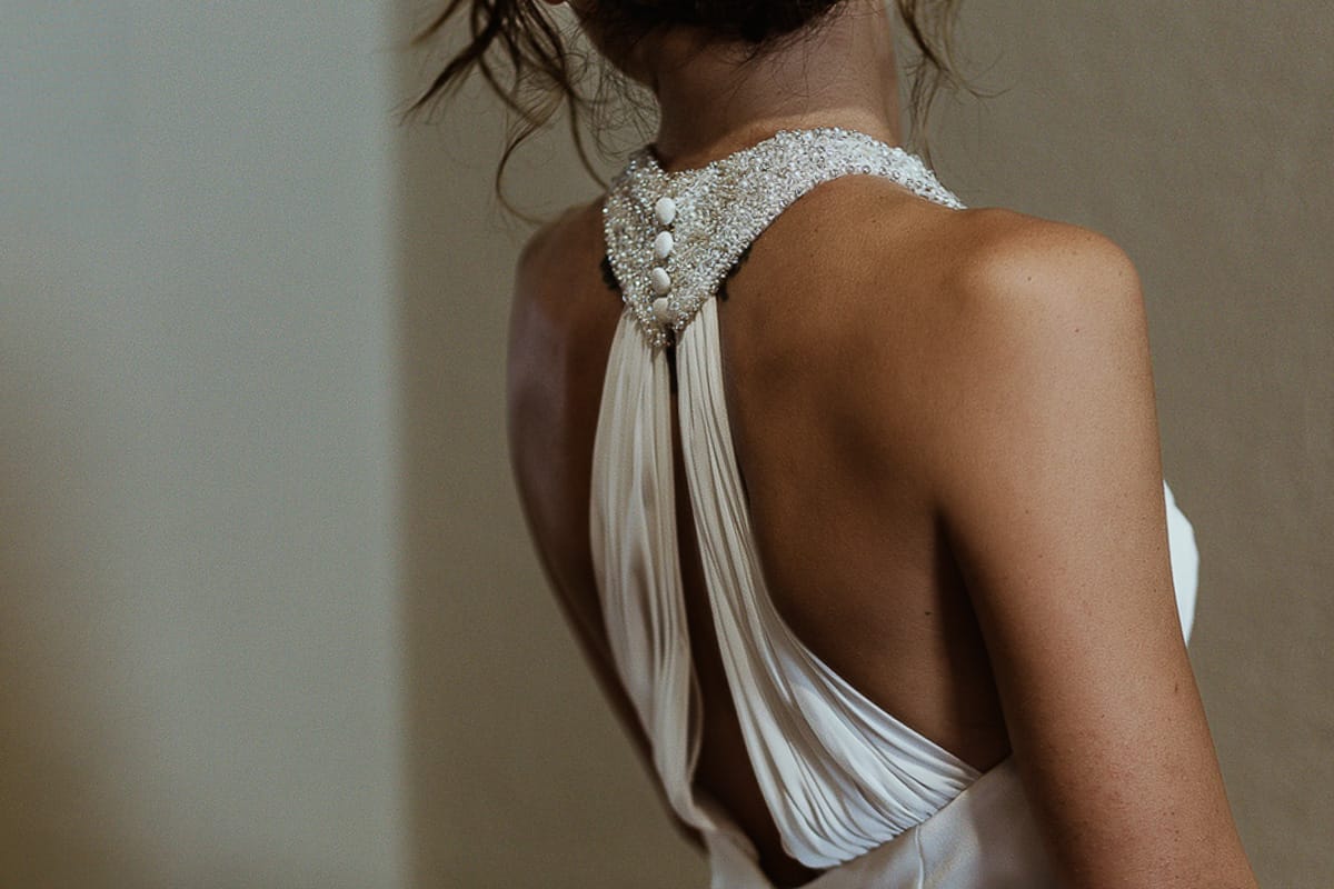 Fotografo matrimonio Torino. Matrimonio eco-consapevole a Cascina Ranverso. Preparazione della sposa a Chieri. Vestizione della sposa. dettaglio dell'abito sulla schiena.