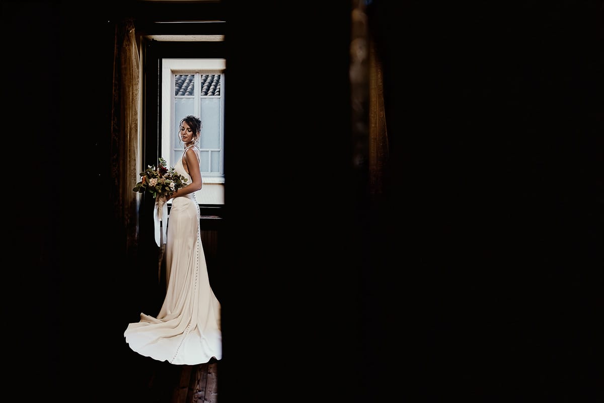 Fotografo matrimonio Torino. Matrimonio eco-consapevole a Cascina Ranverso. Preparazione della sposa a Chieri. Ritratto della sposa alla finestra.
