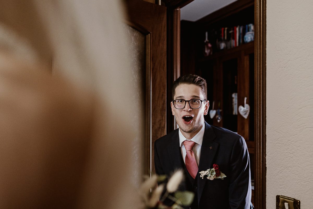 Fotografo matrimonio Torino. Matrimonio eco-consapevole a Cascina Ranverso. Preparazione della sposa a Chieri. Fratello della sposa alla vista della sposa con un'espressione di meraviglia.