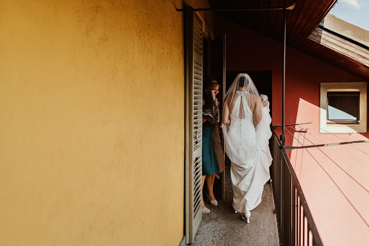 Fotografo matrimonio Torino. Matrimonio eco-consapevole a Cascina Ranverso. Preparazione della sposa a Chieri. Sposa esce dalla casa.Sul balcone.