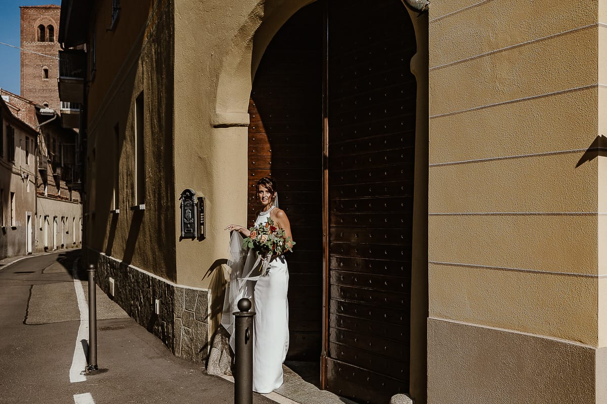 Fotografo matrimonio Torino. Matrimonio eco-consapevole a Cascina Ranverso. Preparazione della sposa a Chieri. Sposa esce dal portone di casa
