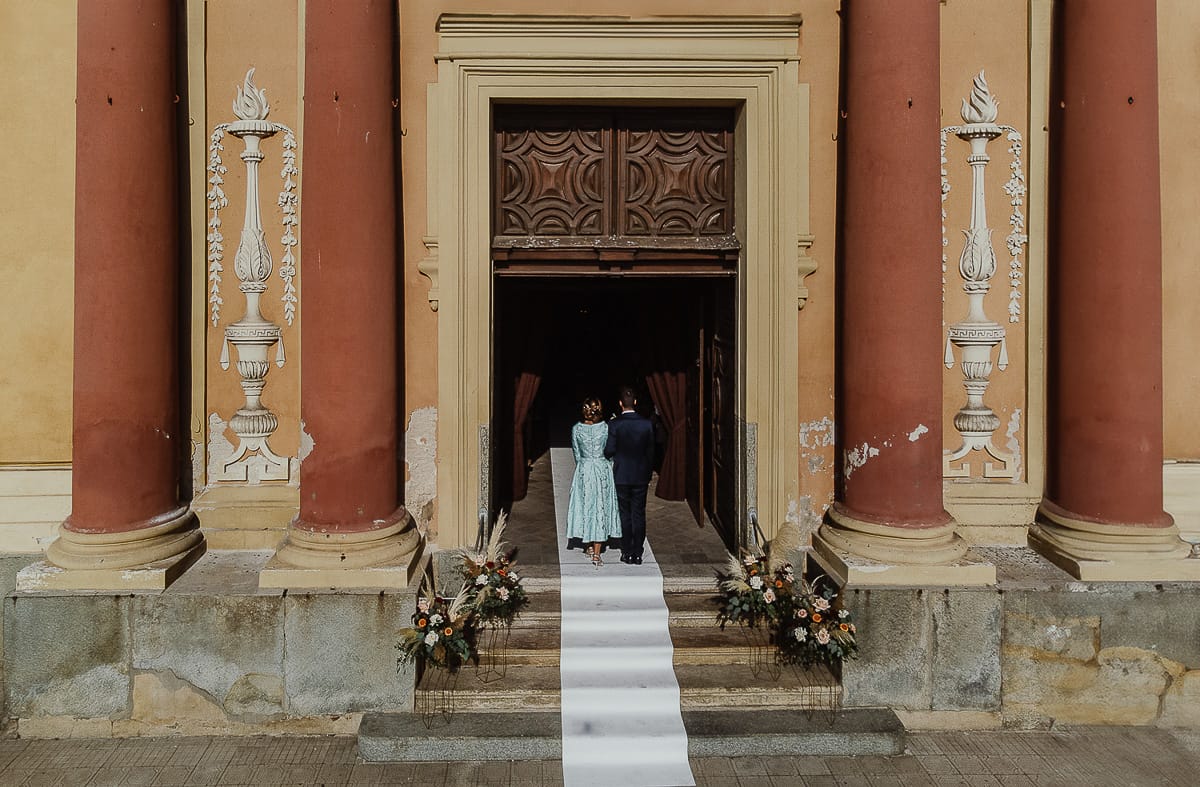 Fotografo matrimonio Torino. Matrimonio eco-consapevole a Cascina Ranverso. Cerimonia a Chieri nella chiesa dei Santi Bernardino e Rocco. Sposo entra con la madre. Foto dal drone