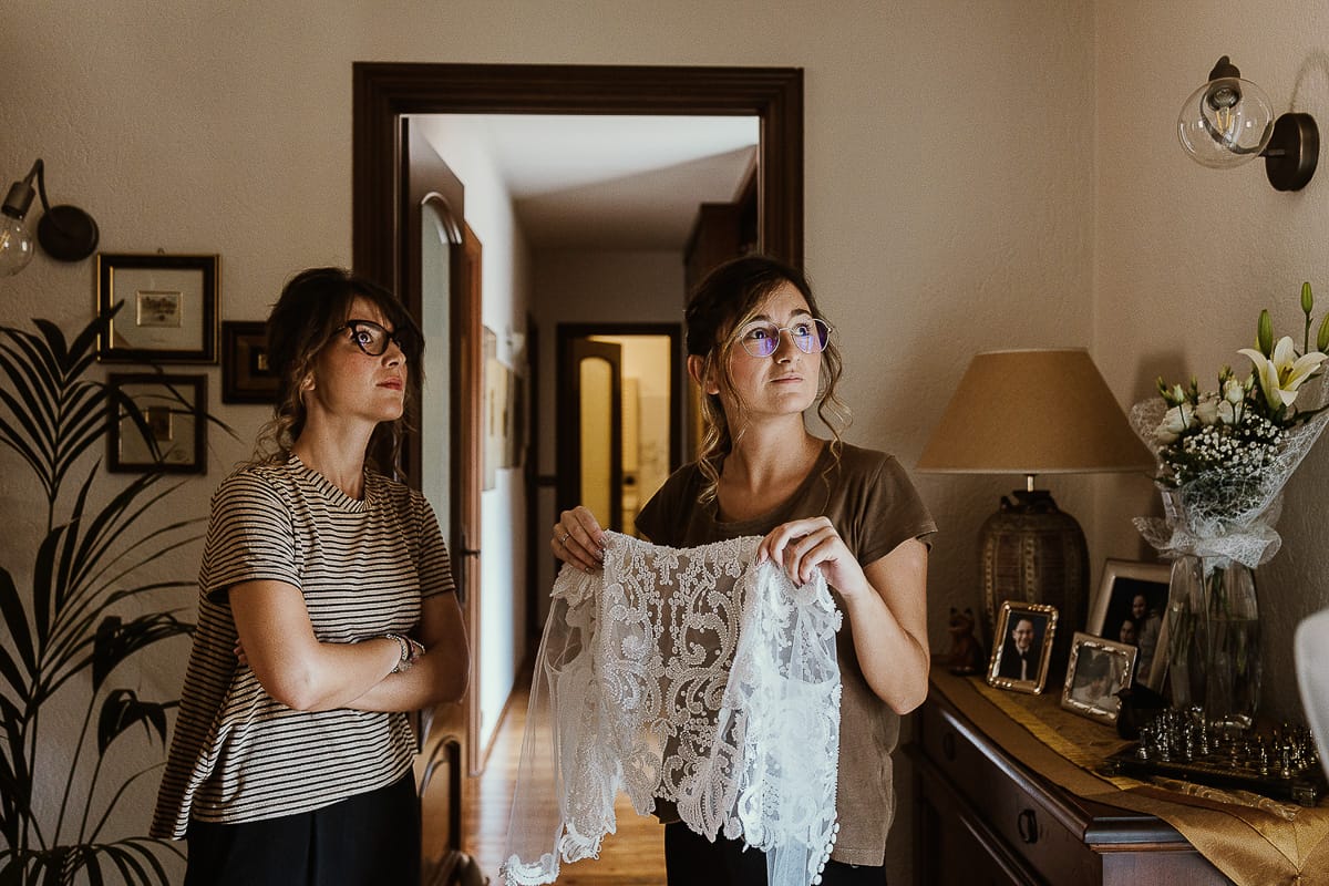 Fotografo matrimonio Torino. Matrimonio eco-consapevole a Cascina Ranverso. Preparazione della sposa a Chieri. Amiche della sposa con il corpino di pizzo della sposa