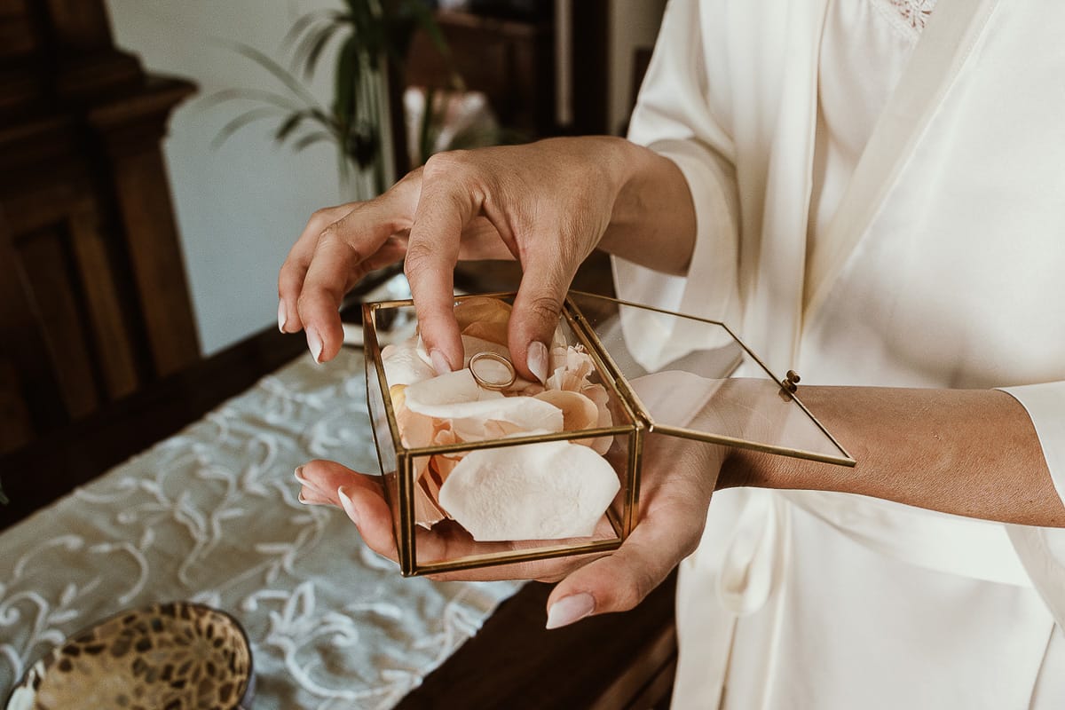 Fotografo matrimonio Torino. Matrimonio eco-consapevole a Cascina Ranverso. Preparazione della sposa a Chieri. Sposa con la scatolina di vetro che contiene gli anelli