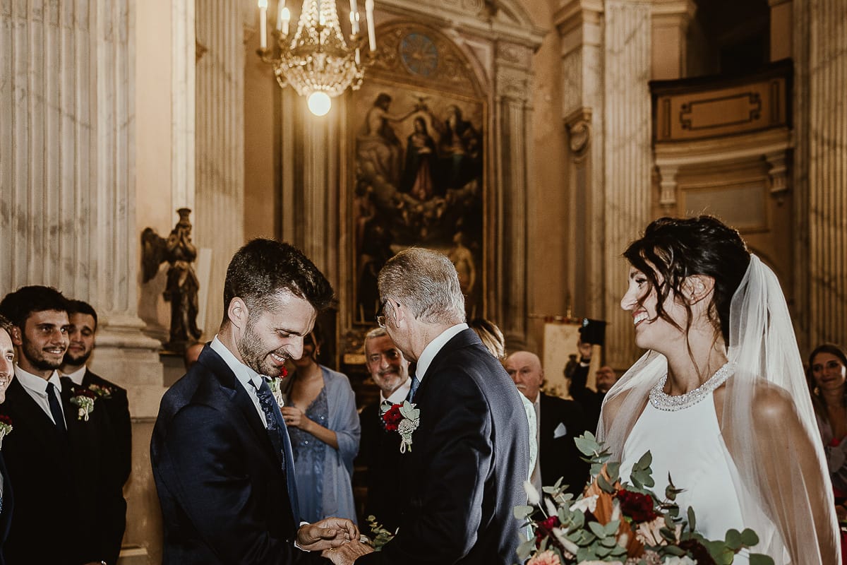 Fotografo matrimonio Torino. Matrimonio eco-consapevole a Cascina Ranverso. Cerimonia a Chieri nella chiesa dei Santi Bernardino e Rocco. Padre della sposa saluta lo sposo.