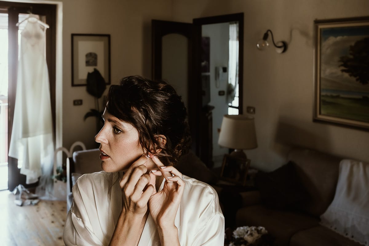 Fotografo matrimonio Torino. Matrimonio eco-consapevole a Cascina Ranverso. Preparazione della sposa a Chieri. Sposa si mette gli orecchini