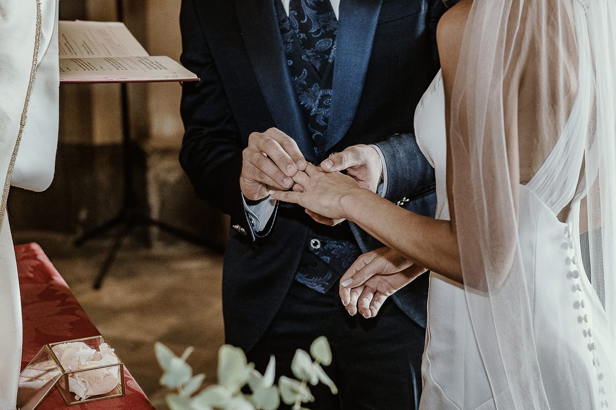 Fotografo matrimonio Torino. Matrimonio eco-consapevole a Cascina Ranverso. Cerimonia a Chieri nella chiesa dei Santi Bernardino e Rocco. Messa. Sposo mette l'anello al dito della sposa.