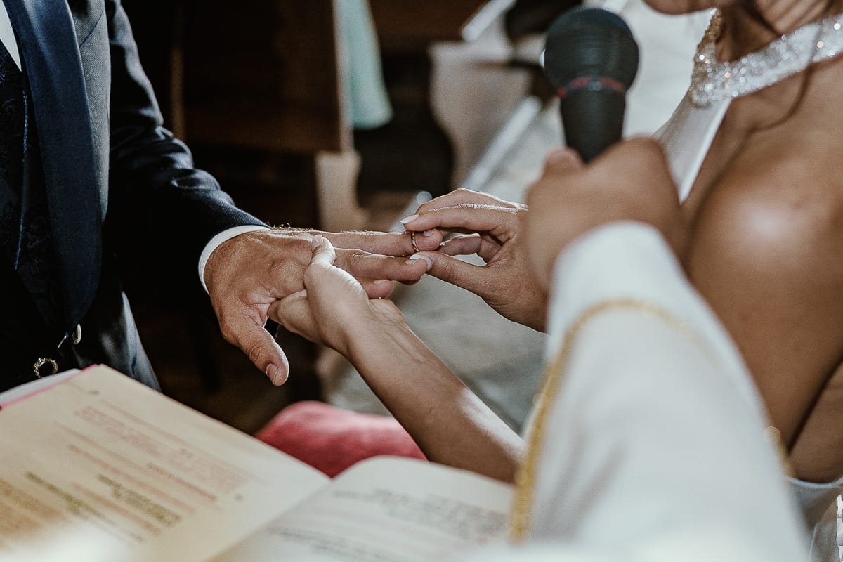 Fotografo matrimonio Torino. Matrimonio eco-consapevole a Cascina Ranverso. Cerimonia a Chieri nella chiesa dei Santi Bernardino e Rocco. Messa. Sposa mette l'anello al dito dello sposo