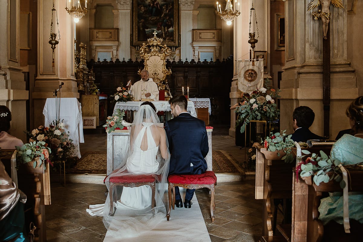 Fotografo matrimonio Torino. Matrimonio eco-consapevole a Cascina Ranverso. Cerimonia a Chieri nella chiesa dei Santi Bernardino e Rocco. Messa. Sposi ripresi da dietro